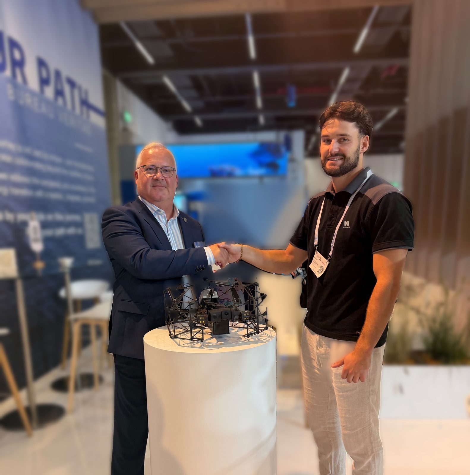 Bureau Veritas and Nolvis representatives shaking hands beside a Nolvis X1 inspection drone at the Bureau Veritas booth during SMM 2026 in Hamburg